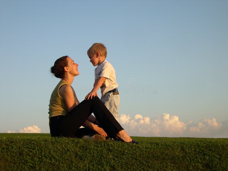 Mother with son on sundown green grass blue sky with clouds. Mother with son on sundown green grass blue sky with clouds