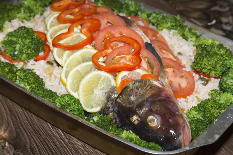 Здоровая вкусная домодельная еда Блюдо витамина рыб аппетитное с овощами Сырцовый карп реки заполненный с рисом, свежими томатами стоковые изображения rf Здоровая вкусная домодельная еда Блюдо витамина рыб аппетитное с овощами Сырцовый карп реки заполненный с рисом, свежими томатами стоковые изображения rf