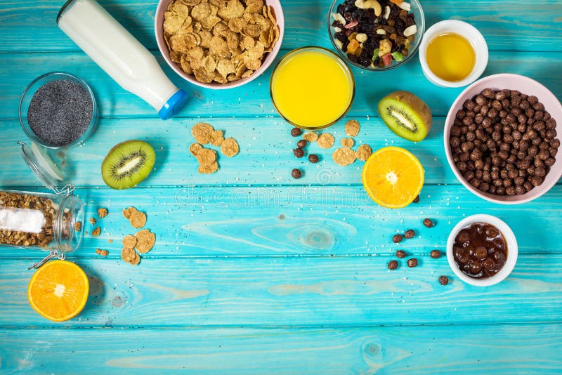 Здоровый завтрак с шаром хлопьев, апельсинового сока, granola, молока, варенья и плодоовощей на голубой деревянной предпосылке сб стоковые изображения Здоровый завтрак с шаром хлопьев, апельсинового сока, granola, молока, варенья и плодоовощей на голубой деревянной предпосылке сб стоковые изображения