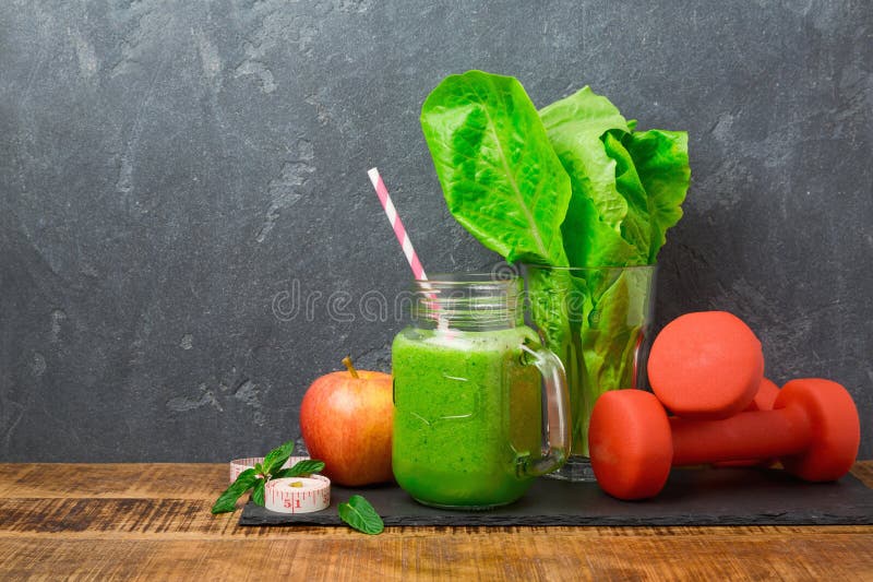 Зеленый smoothie с яблоком, салатом и гантелями над темной предпосылкой Вытрезвитель, dieting, вегетарианец, фитнес или здоровая стоковые изображения rf Зеленый smoothie с яблоком, салатом и гантелями над темной предпосылкой Вытрезвитель, dieting, вегетарианец, фитнес или здоровая стоковые изображения rf