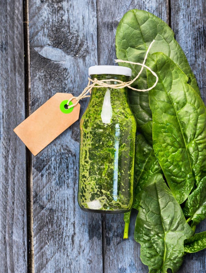 Зеленый smoothie шпината в стеклянной бутылке с знаком на голубой деревянной предпосылке стоковое изображение Зеленый smoothie шпината в стеклянной бутылке с знаком на голубой деревянной предпосылке стоковое изображение