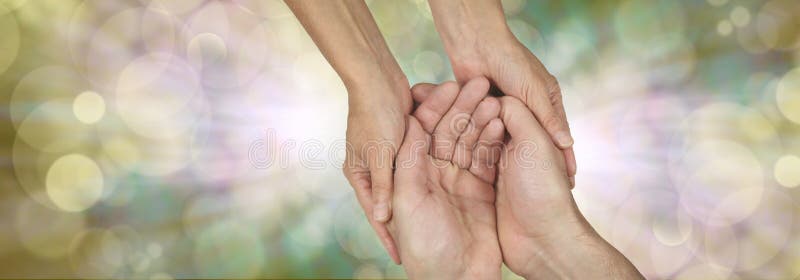 Wide banner with a woman's hands holding a man's cupped hands in a needy gesture on a bokeh and light burst background and plenty of copy space either side. Wide banner with a woman's hands holding a man's cupped hands in a needy gesture on a bokeh and light burst background and plenty of copy space either side