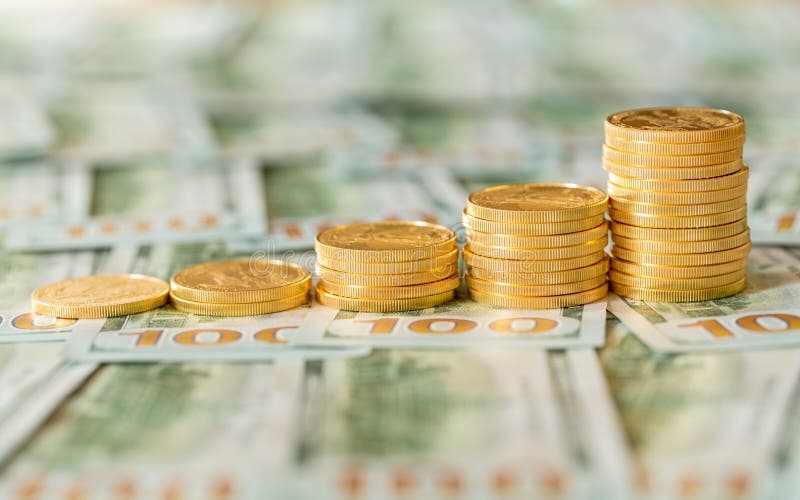 Золотые монетки штабелированные на новых долларовых банкнотах дизайна $100 стоковая фотография rf