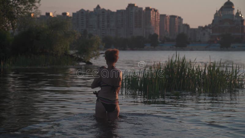 зрелая женщина с маленькой старой собачкой плавают в воде. пожилая самка проводит лето на реке со своей собакой. день отпуска акции видеоматериалы