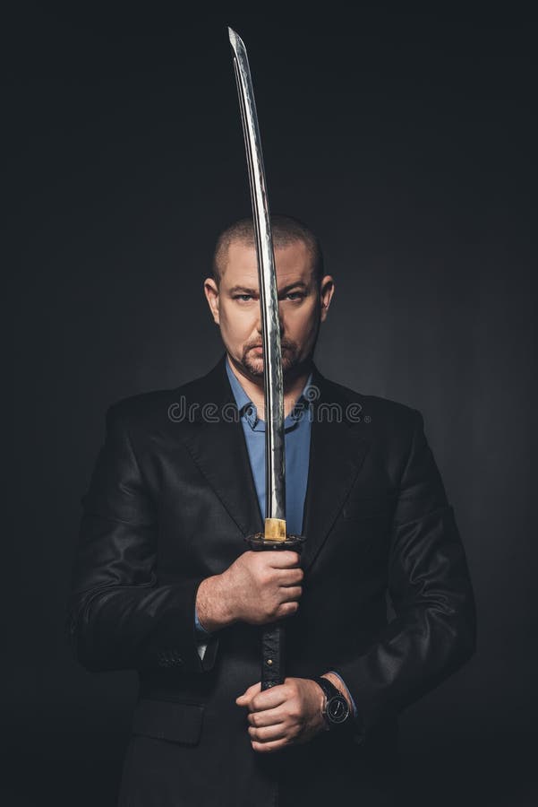 зрелый человек в костюме держа японскую шпагу katana перед его стороной стоковая фотография rf зрелый человек в костюме держа японскую шпагу katana перед его стороной стоковая фотография rf