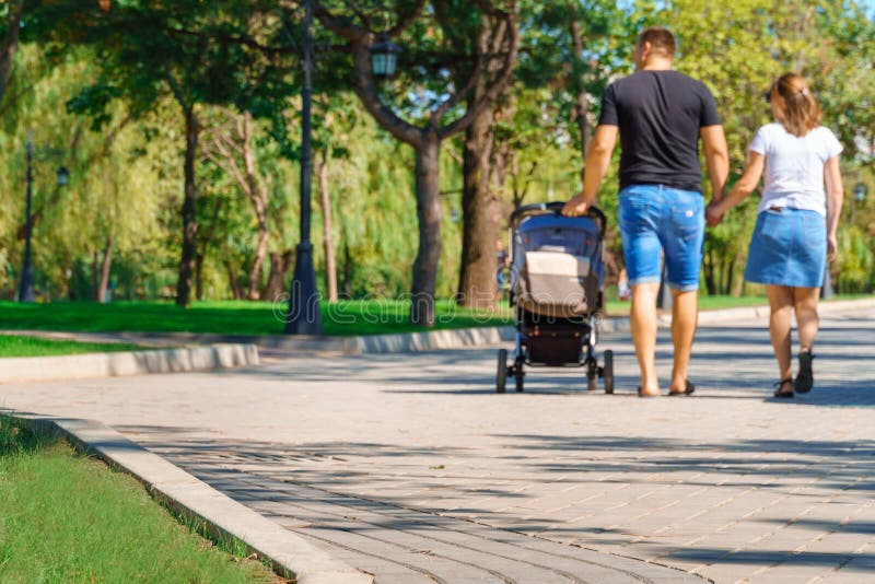 И дети людей, играющих в городском парке на лужайках зеленого летнего ...