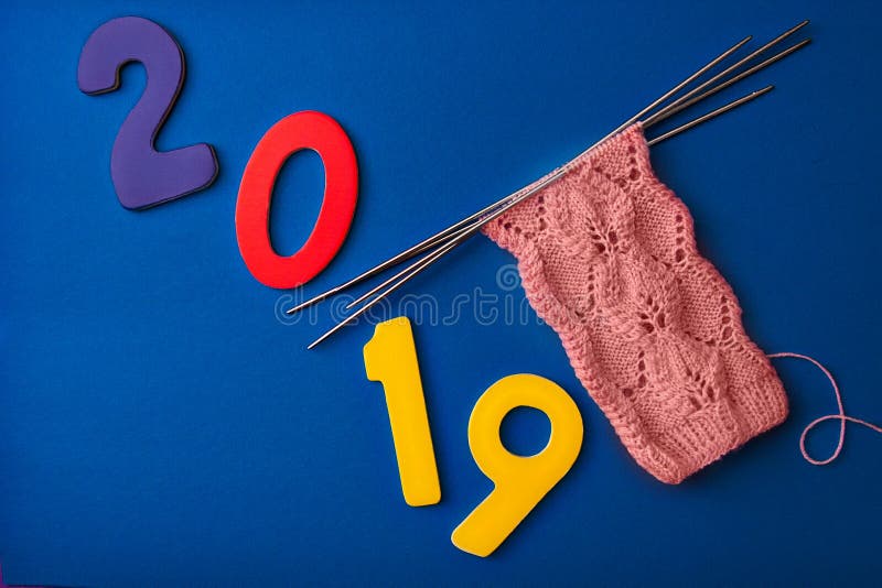 2019 и розовые носки сделанные из шерстей, связали с openwork картиной на 4 вязать иглах на голубой предпосылке стоковые фото