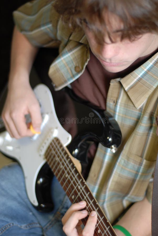 Fourteen year old teenage boy playing or practicing guitar. Fourteen year old teenage boy playing or practicing guitar