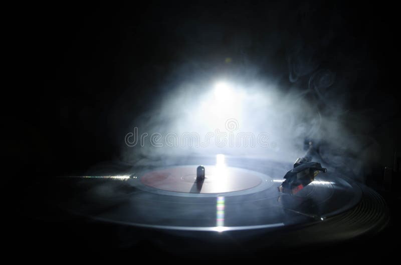 Turntable vinyl record player. Retro audio equipment for disc jockey. Sound technology for DJ to mix & play music. Vinyl record being played against burning fire background with smoke. Turntable vinyl record player. Retro audio equipment for disc jockey. Sound technology for DJ to mix & play music. Vinyl record being played against burning fire background with smoke