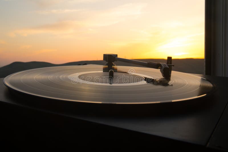 Turntable vinyl record player on the background of a sunset over the mountains. Sound technology for DJ to mix & play music. Black vinyl record. Vintage vinyl record player. Needle on a vinyl record. Turntable vinyl record player on the background of a sunset over the mountains. Sound technology for DJ to mix & play music. Black vinyl record. Vintage vinyl record player. Needle on a vinyl record