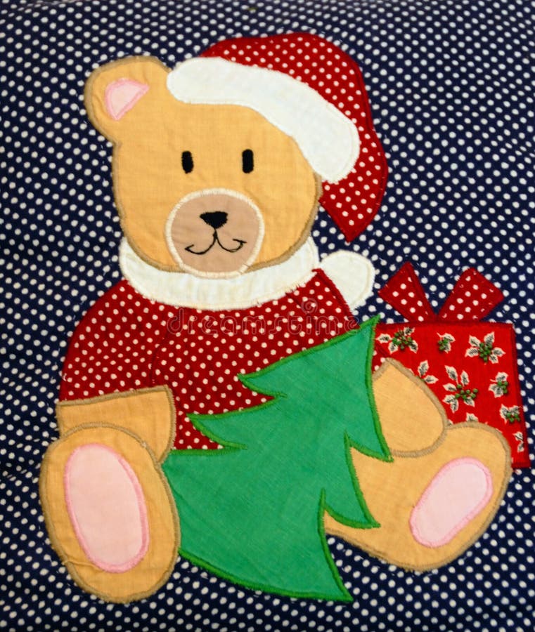 A quilted Christmas teddy bear surrounded with presents on a blue polka dotted background. A quilted Christmas teddy bear surrounded with presents on a blue polka dotted background.