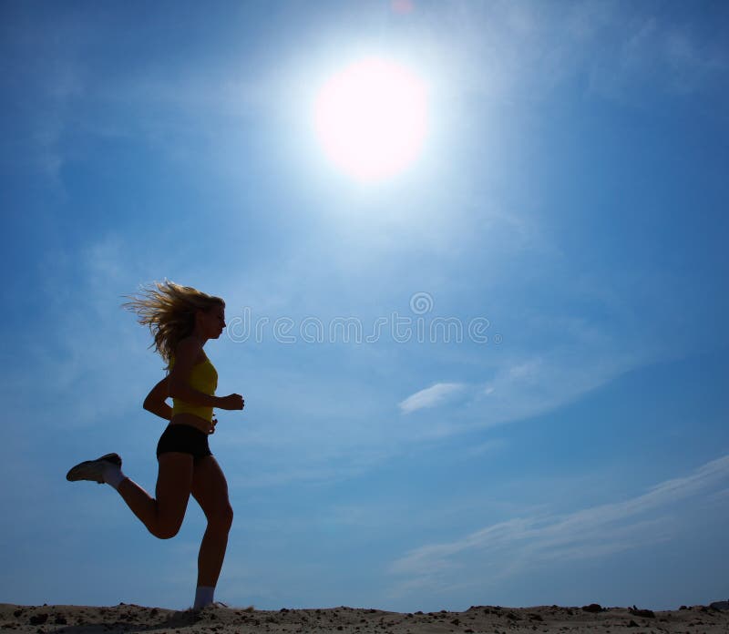 A fast running woman silhouetted against sun and sky. Her hair is windblown. A fast running woman silhouetted against sun and sky. Her hair is windblown.