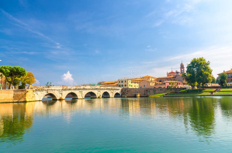 Известный каменный мост Ponte di Tiberio Augustus Tiberius свода над речной водой Marecchia, старыми домами зданий в Римини стоковая фотография rf Известный каменный мост Ponte di Tiberio Augustus Tiberius свода над речной водой Marecchia, старыми домами зданий в Римини стоковая фотография rf