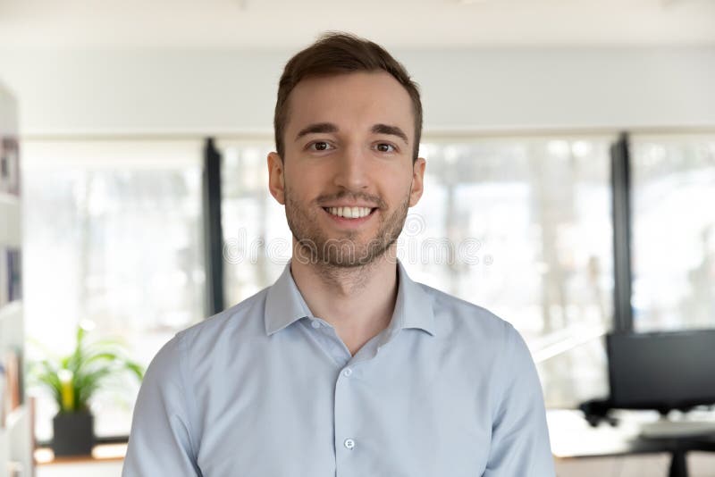 Profile picture of happy young Caucasian male employee worker look at camera posing in office workplace, headshot portrait of smiling businessman boss show confidence and success, leadership concept. Profile picture of happy young Caucasian male employee worker look at camera posing in office workplace, headshot portrait of smiling businessman boss show confidence and success, leadership concept