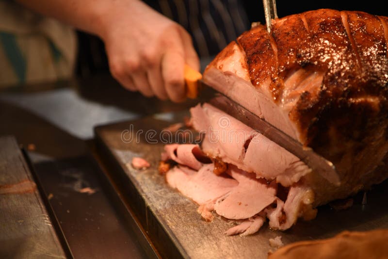 Изображение фотографии еды сваренного соединения gammon или ветчины жаркого мяса при рука держа разделочный нож и отрезая обедающ стоковое изображение Изображение фотографии еды сваренного соединения gammon или ветчины жаркого мяса при рука держа разделочный нож и отрезая обедающ стоковое изображение