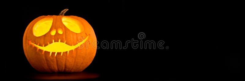 Illuminated Halloween Jack-o-lantern pumpkin, black panoramic background with copy space. Illuminated Halloween Jack-o-lantern pumpkin, black panoramic background with copy space