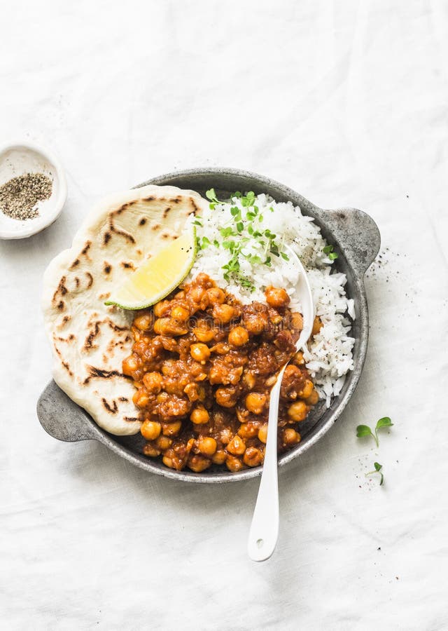 Индийское пряное карри нутов с рисом и naan хлебом в лотке на светлой предпосылке, взгляде сверху стоковое изображение rf Индийское пряное карри нутов с рисом и naan хлебом в лотке на светлой предпосылке, взгляде сверху стоковое изображение rf