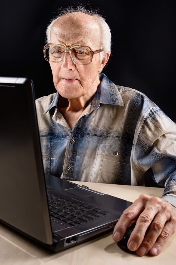 Intellectual senior man works on the laptop late at night. Intellectual senior man works on the laptop late at night