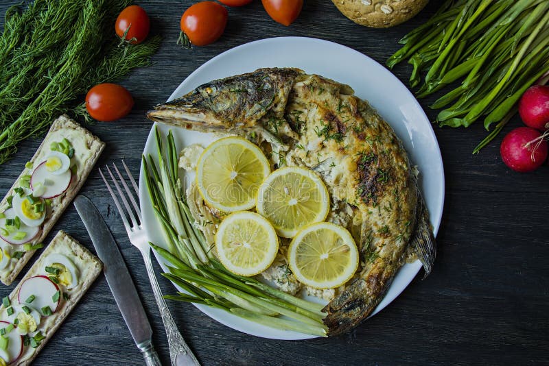 Испеченная щука в печи, украшенной с овощами и травами Служение на плите E Темная деревянная предпосылка стоковое изображение Испеченная щука в печи, украшенной с овощами и травами Служение на плите E Темная деревянная предпосылка стоковое изображение