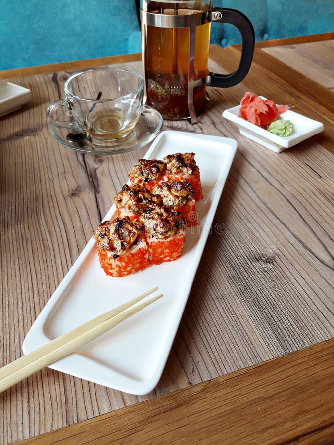 Испеченные крены морепродуктов в белой плите с палочками, имбирем и wasabi на деревянном столе стоковое изображение rf Испеченные крены морепродуктов в белой плите с палочками, имбирем и wasabi на деревянном столе стоковое изображение rf