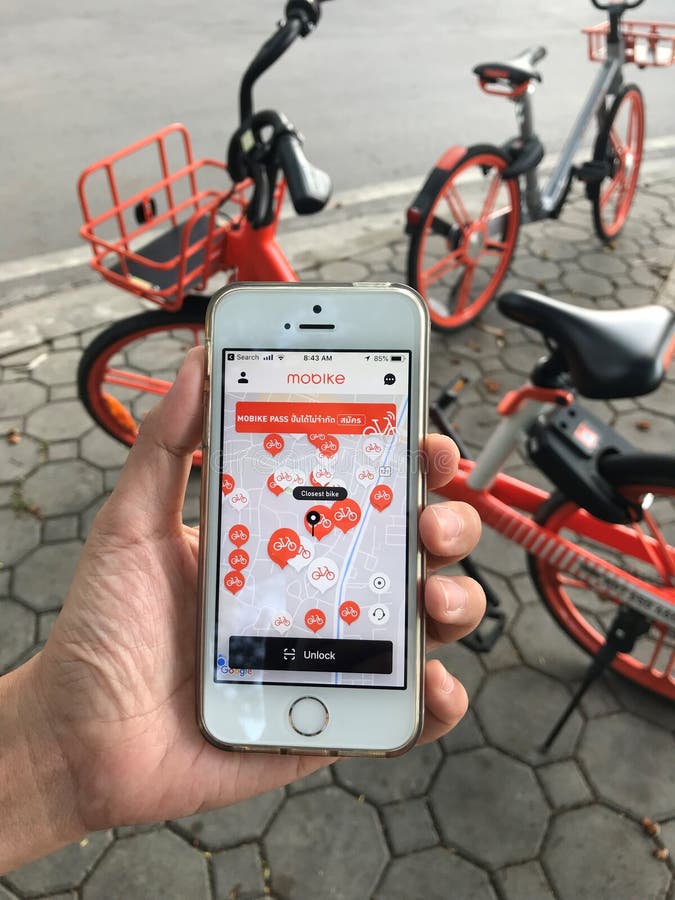 Используя применение на iPhone для велосипеда “mobike†арендного который паркует на тропе около дороги стоковое фото Используя применение на iPhone для велосипеда “mobike†арендного который паркует на тропе около дороги стоковое фото