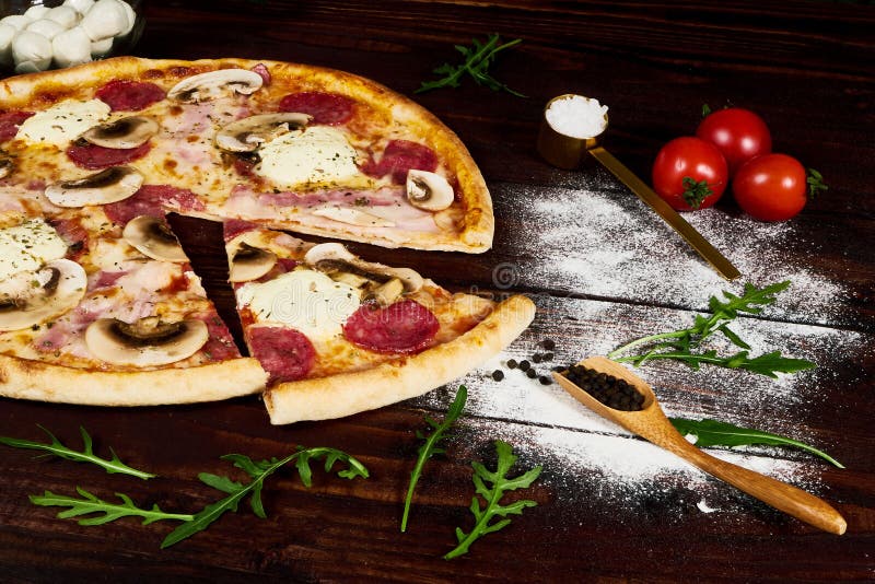 Итальянский фаст-фуд Очень вкусная горячая пицца отрезанная и послуженная на деревянном диске с ингридиентами, конце вверх по взг стоковые изображения Итальянский фаст-фуд Очень вкусная горячая пицца отрезанная и послуженная на деревянном диске с ингридиентами, конце вверх по взг стоковые изображения
