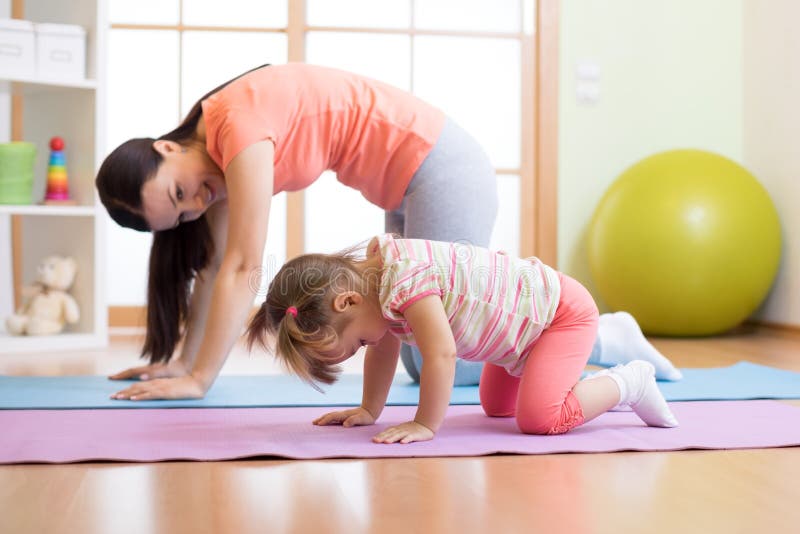 Mother and child daughter practicing yoga together in living room at home. Sport and family concept. Mother and child daughter practicing yoga together in living room at home. Sport and family concept.