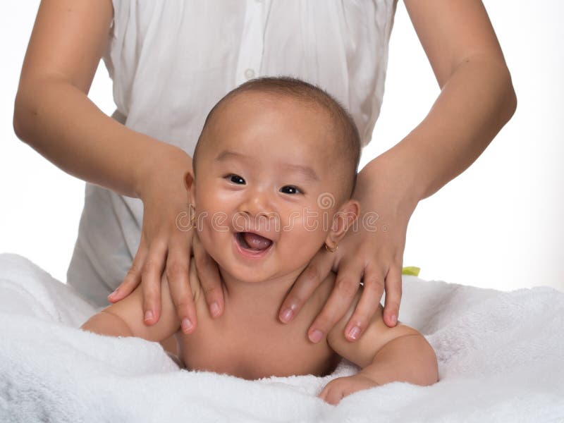 Baby is getting back massage done by mother, baby seem to enjoy this from her expression laughing and the image are not isolated in photoshop, just white background on studio. Baby is getting back massage done by mother, baby seem to enjoy this from her expression laughing and the image are not isolated in photoshop, just white background on studio