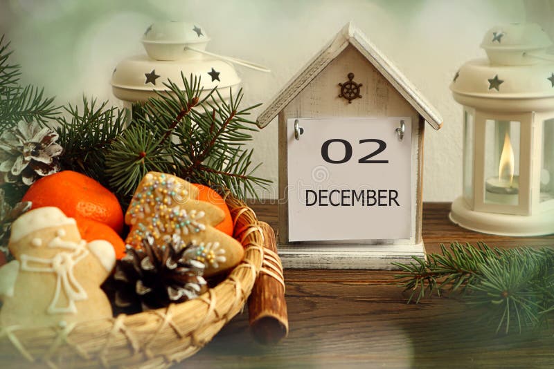 Calendar for December 2: decorative house with the name of the month december, number 02, holiday gingerbread, tangerines, cones on a platter, needles, bokeh. Calendar for December 2: decorative house with the name of the month december, number 02, holiday gingerbread, tangerines, cones on a platter, needles, bokeh.
