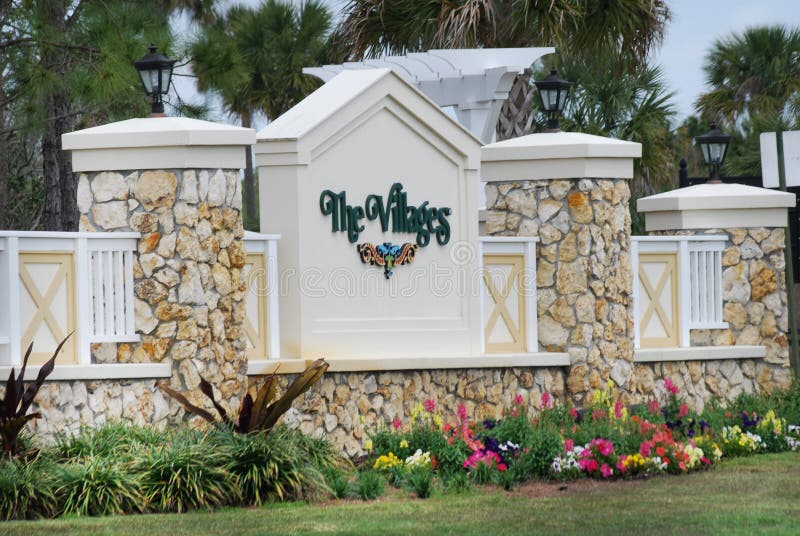 Stone entrance to The Villages with brightly colored spring flowers in Florida. Stone entrance to The Villages with brightly colored spring flowers in Florida.