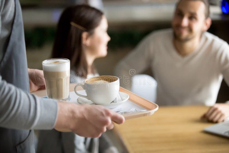 Капучино и latte сервировки официантки, который нужно соединить в кафе, крупном плане стоковые фотографии rf Капучино и latte сервировки официантки, который нужно соединить в кафе, крупном плане стоковые фотографии rf