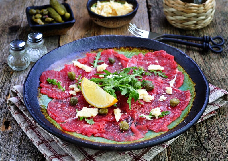 Карпаччо из говядины с каперсами, пармезаном, arugula, лимоном и оливковым маслом стоковые изображения Карпаччо из говядины с каперсами, пармезаном, arugula, лимоном и оливковым маслом стоковые изображения