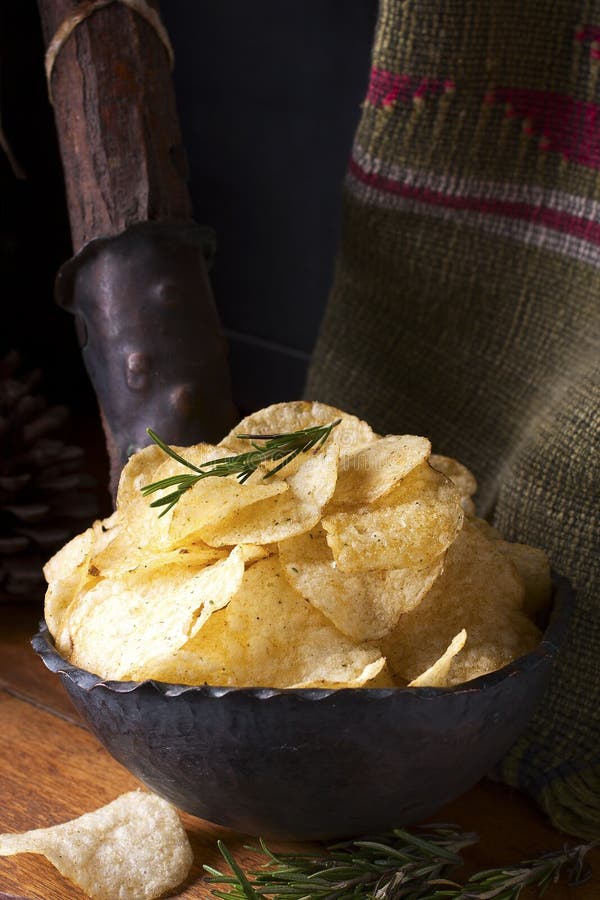 Potato chips with rosemary on a wooden table. Potato chips with rosemary on a wooden table.