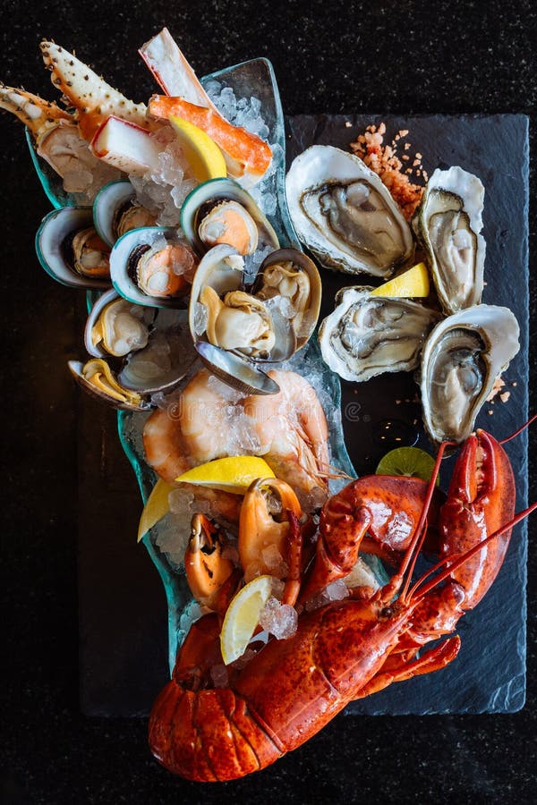Кипеть омар, свежие устрицы, креветки, мидии и clams, который служат в черной каменной плите стоковое изображение rf Кипеть омар, свежие устрицы, креветки, мидии и clams, который служат в черной каменной плите стоковое изображение rf