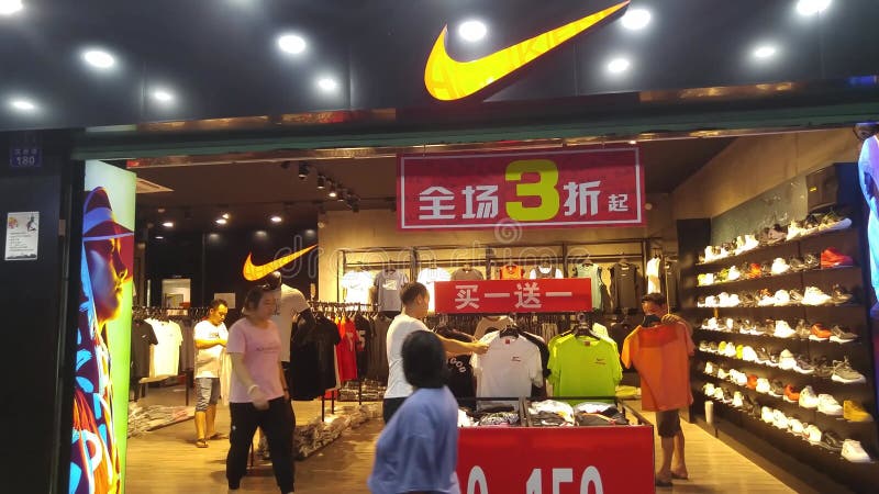 Китай Шеньчжэнь : Магазины спортивной одежды Nike предлагают скидки и клиенты покупают одежду и обувь