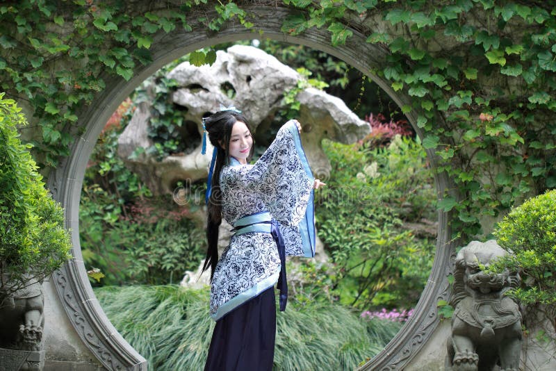 Китайская женщина в традиционном голубом и белом платье Hanfu стоя в середине красивого строба стоковые изображения Китайская женщина в традиционном голубом и белом платье Hanfu стоя в середине красивого строба стоковые изображения