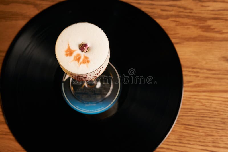 Classical Lucy cocktail on vinyl tray background. Cocktail with Gin, Yogurt, liqueur, Lychee puree, Cardamom syrup, egg white, Lemon juice. Sweet cocktail with spicy taste, close-up. Classical Lucy cocktail on vinyl tray background. Cocktail with Gin, Yogurt, liqueur, Lychee puree, Cardamom syrup, egg white, Lemon juice. Sweet cocktail with spicy taste, close-up