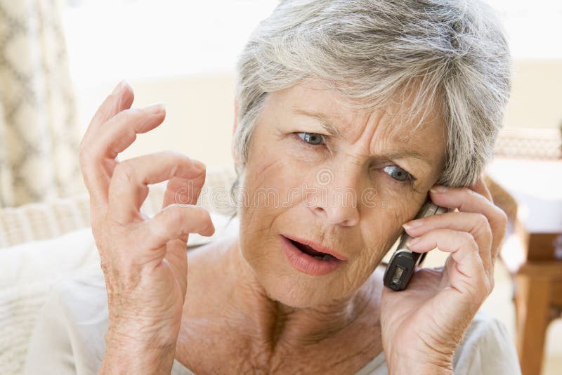 Woman indoors using cellular phone frowning. Woman indoors using cellular phone frowning.