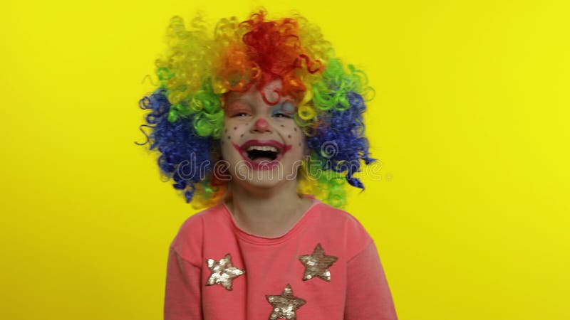 Клоун девушки маленького ребенка в парике rainbow, делающих глупые лица. Весело улыбаясь, чтобы смеяться. Хэллоуин сток-видео