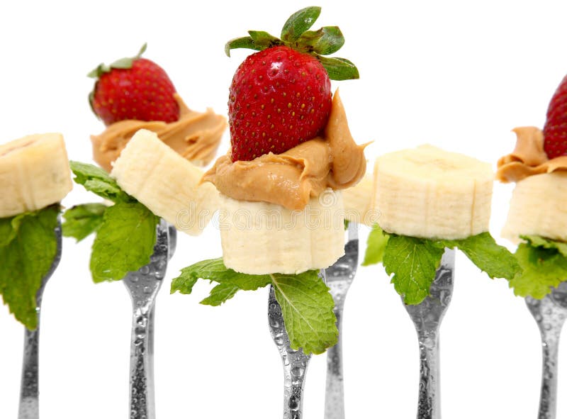 Banana slices, peanut butter and whole strawberries on forks with mint leaves. Banana slices, peanut butter and whole strawberries on forks with mint leaves.