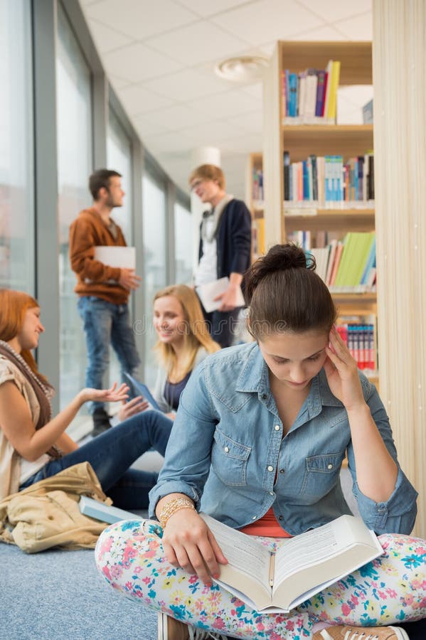 Книга чтения девушки в библиотеке колледжа стоковые изображения