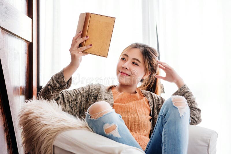 Книга чтения молодой женщины дома с счастливой стороной Smiley и реальное стоковые изображения rf Книга чтения молодой женщины дома с счастливой стороной Smiley и реальное стоковые изображения rf