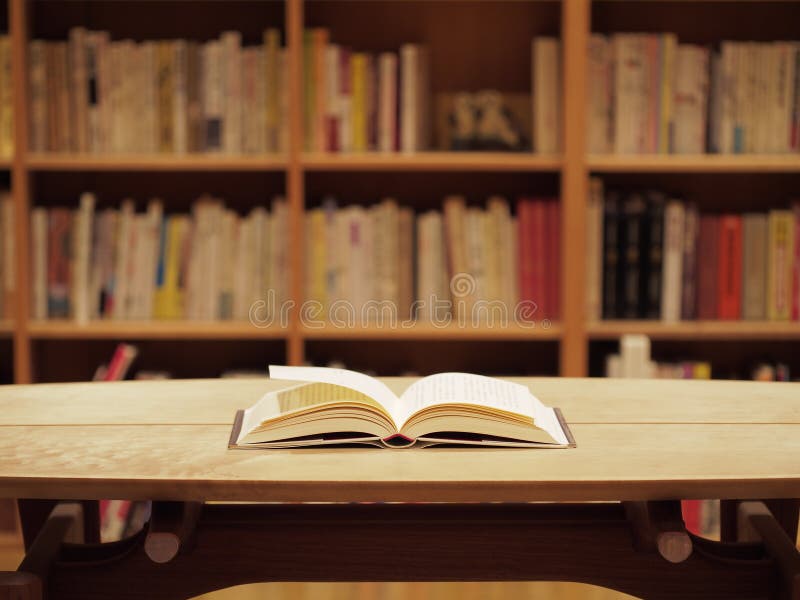 Bookshelf and an open book on a wooden table. Bookshelf and an open book on a wooden table