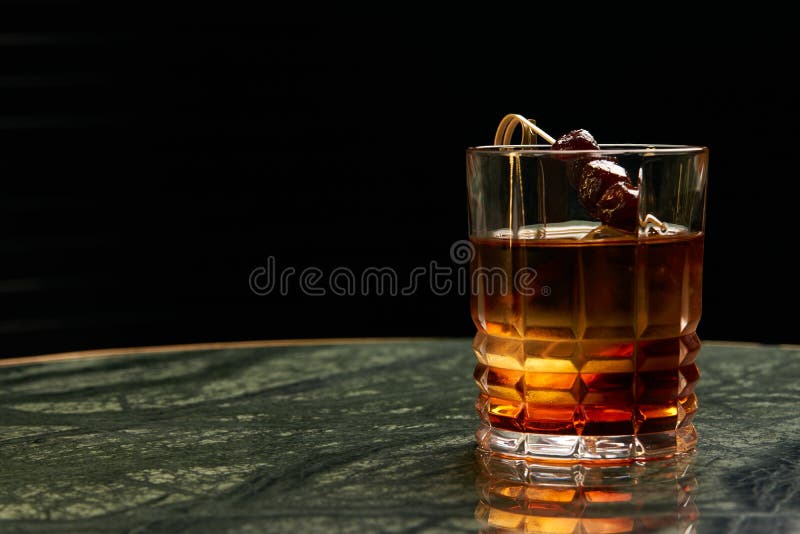 Artichoke Negroni cocktail on bar table. Tart, man`s cocktail with Gin alcohol , Rosso, Cynar, close-up. Artichoke Negroni cocktail on bar table. Tart, man`s cocktail with Gin alcohol , Rosso, Cynar, close-up