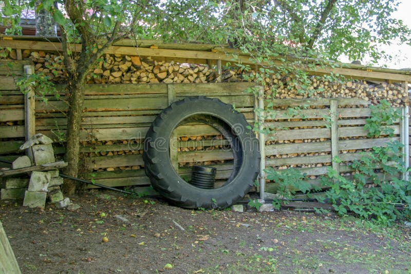 Колесо от трактора полагается против woodpile стоковое фото Колесо от трактора полагается против woodpile стоковое фото