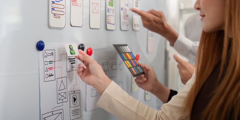 Коллектив разработчиков UX UI улучшает дизайн приложений на доске, иллюстрирующей динамическое творчество и совместную работу стоковые фотографии rf