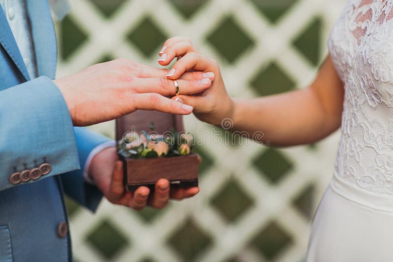 Кольца обменом новобрачных, groom кладут кольцо на руку ` s невесты стоковая фотография rf Кольца обменом новобрачных, groom кладут кольцо на руку ` s невесты стоковая фотография rf