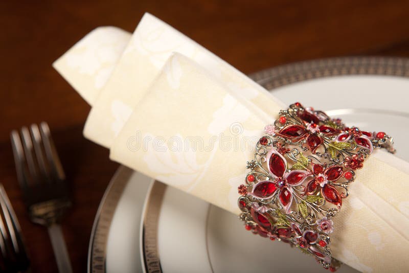 Cream colored festive napkin with ornate fancy napkin ring on a holiday table. Cream colored festive napkin with ornate fancy napkin ring on a holiday table