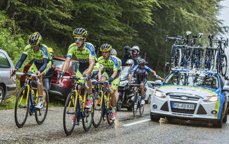 Col du Platzerwasel, France - July 14, 2014: Members of the Team Thinkoff - Saxo help Alberto Contador to climb the road to mountain pass Platzerwasel in Vosges mountains, during the stage 10 of Le Tour de France 2014. In this image Contador rides with a left tibial fracture after falling few kilometers before. He abandoned the race before reaching the summit of this climb. Col du Platzerwasel, France - July 14, 2014: Members of the Team Thinkoff - Saxo help Alberto Contador to climb the road to mountain pass Platzerwasel in Vosges mountains, during the stage 10 of Le Tour de France 2014. In this image Contador rides with a left tibial fracture after falling few kilometers before. He abandoned the race before reaching the summit of this climb.