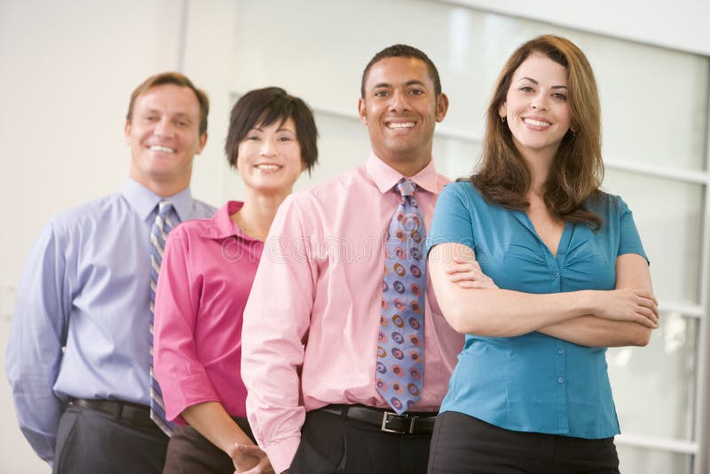 Business team standing indoors smiling at camera. Business team standing indoors smiling at camera.